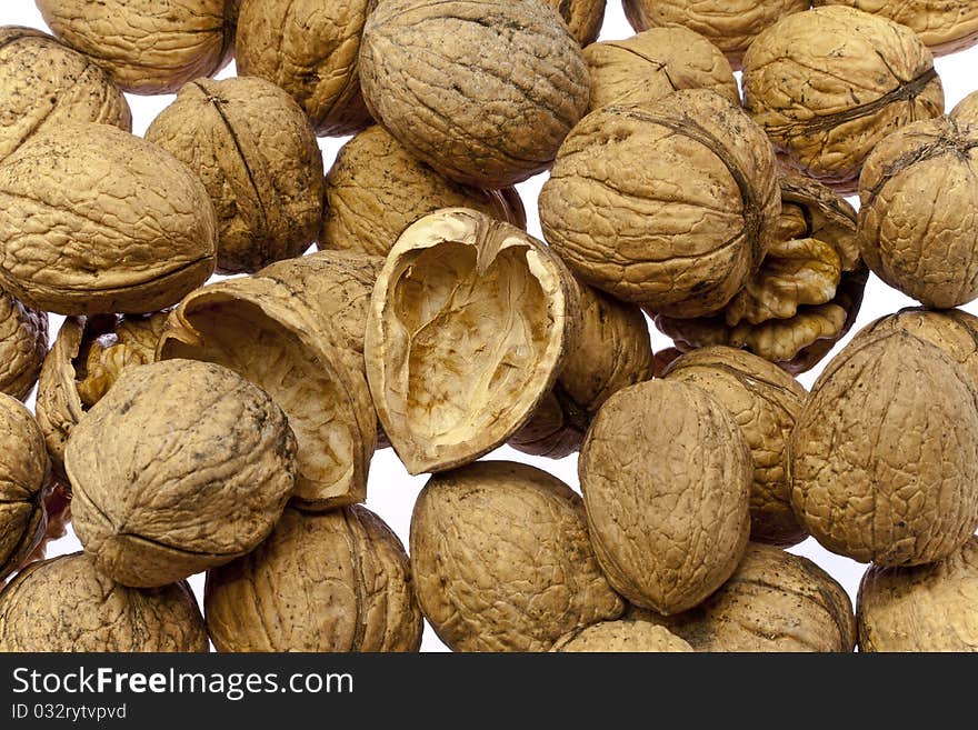 Whole walnuts and cracked walnuts as background texture but on a white surface