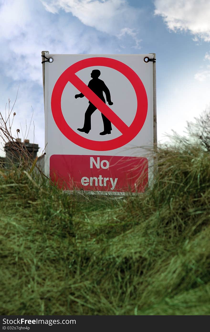 No entry sign on grass with clouds