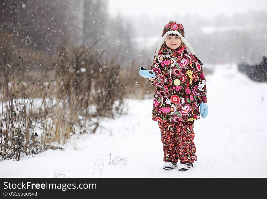 Adorable small girl in colorful winter clothers catches snowflakes in strong snowfall. Adorable small girl in colorful winter clothers catches snowflakes in strong snowfall