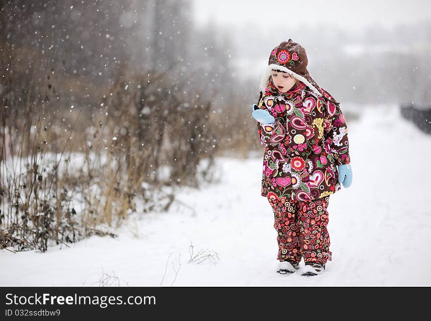 Adorable small girl in colorful winter clothers catches snowflakes in strong snowfall. Adorable small girl in colorful winter clothers catches snowflakes in strong snowfall