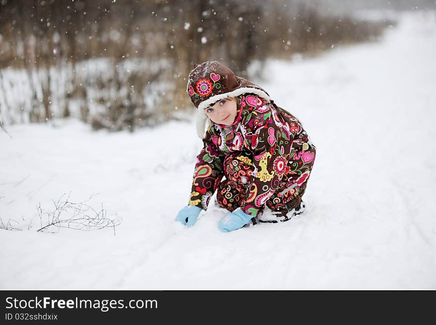 Adorable small girl in colorful winter clothes plays with snow in strong snowfall. Adorable small girl in colorful winter clothes plays with snow in strong snowfall