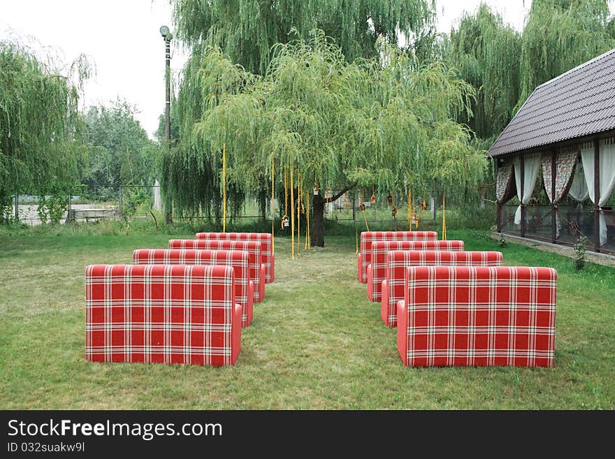 Rows of red empty chairs on a lawn before a wedding or ceremony