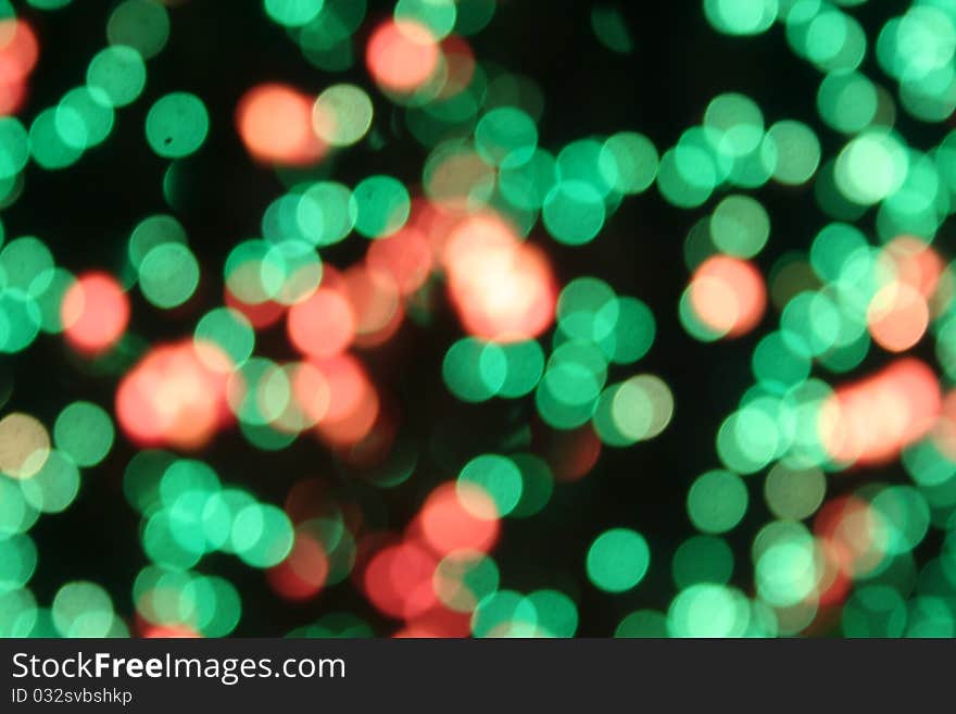 Abstract blur of green lights with a scattering of pinkish peach against a black background. Abstract blur of green lights with a scattering of pinkish peach against a black background.