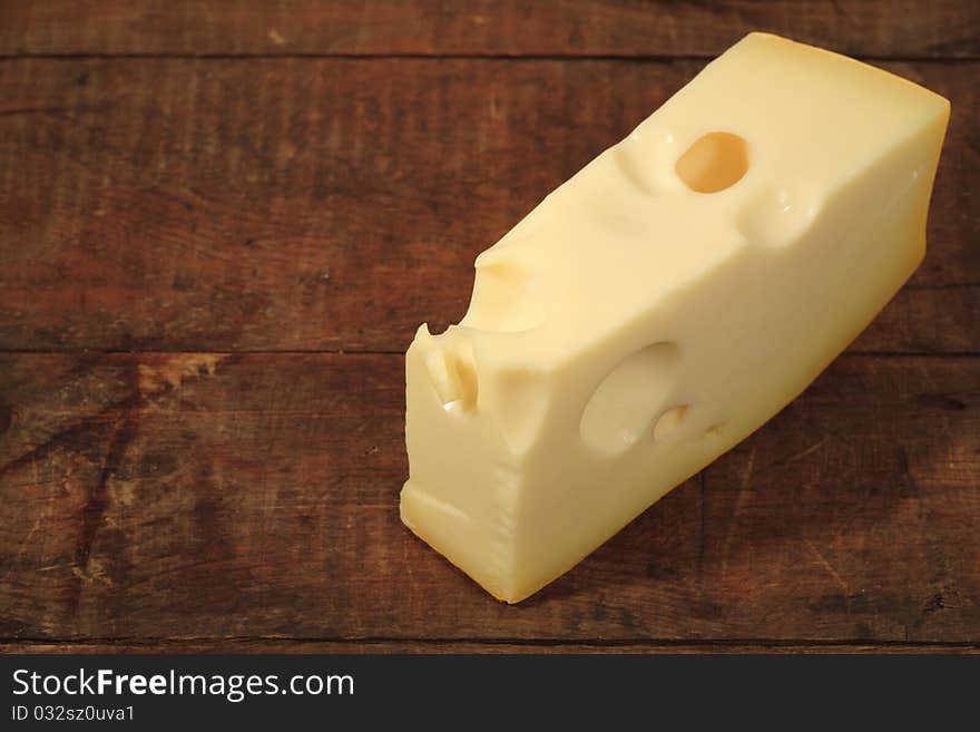 A piece of cheese lying on wooden background with copy space