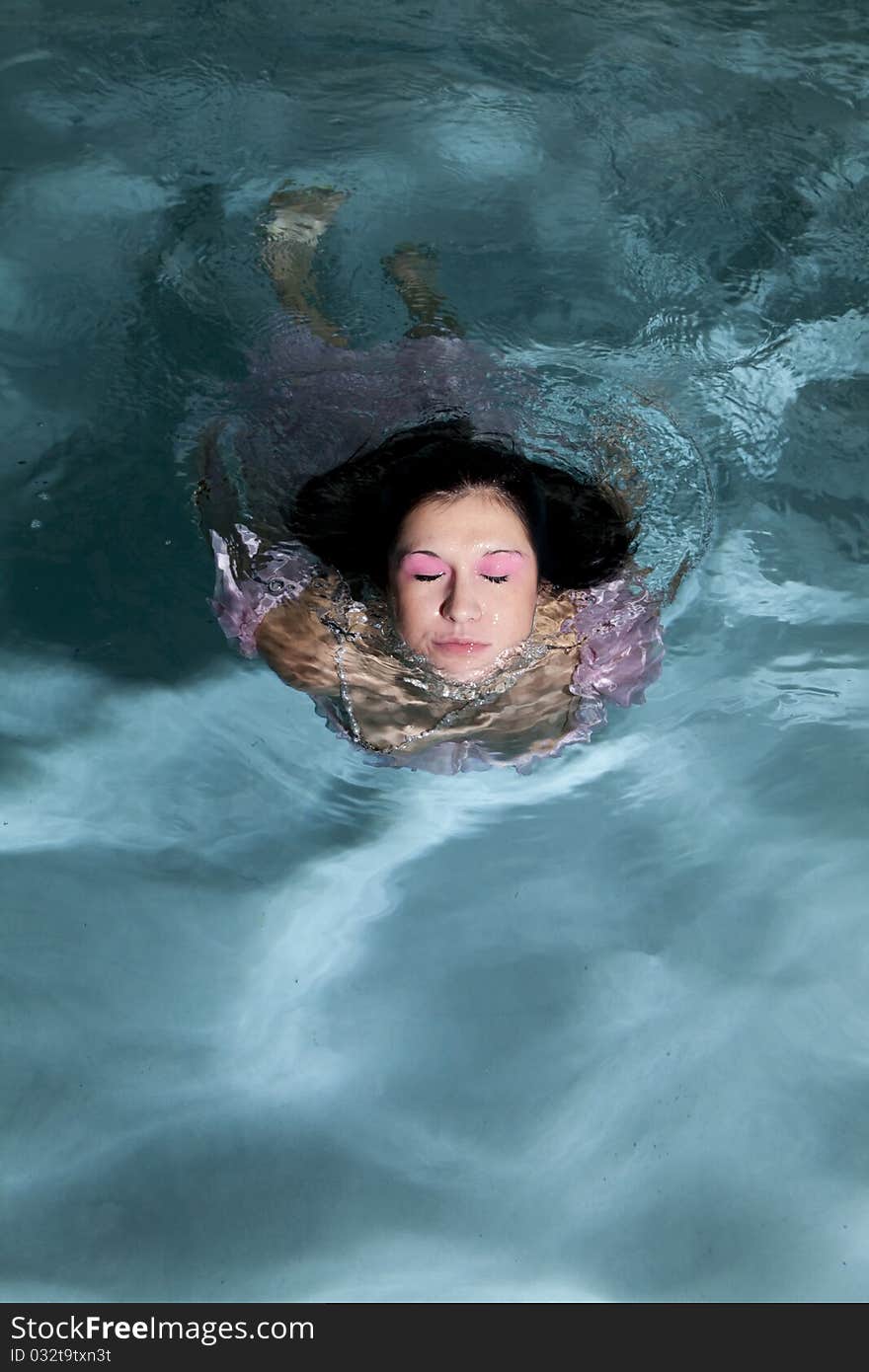 A woman in a dress in the water coming out of it with her eyes closed. A woman in a dress in the water coming out of it with her eyes closed.