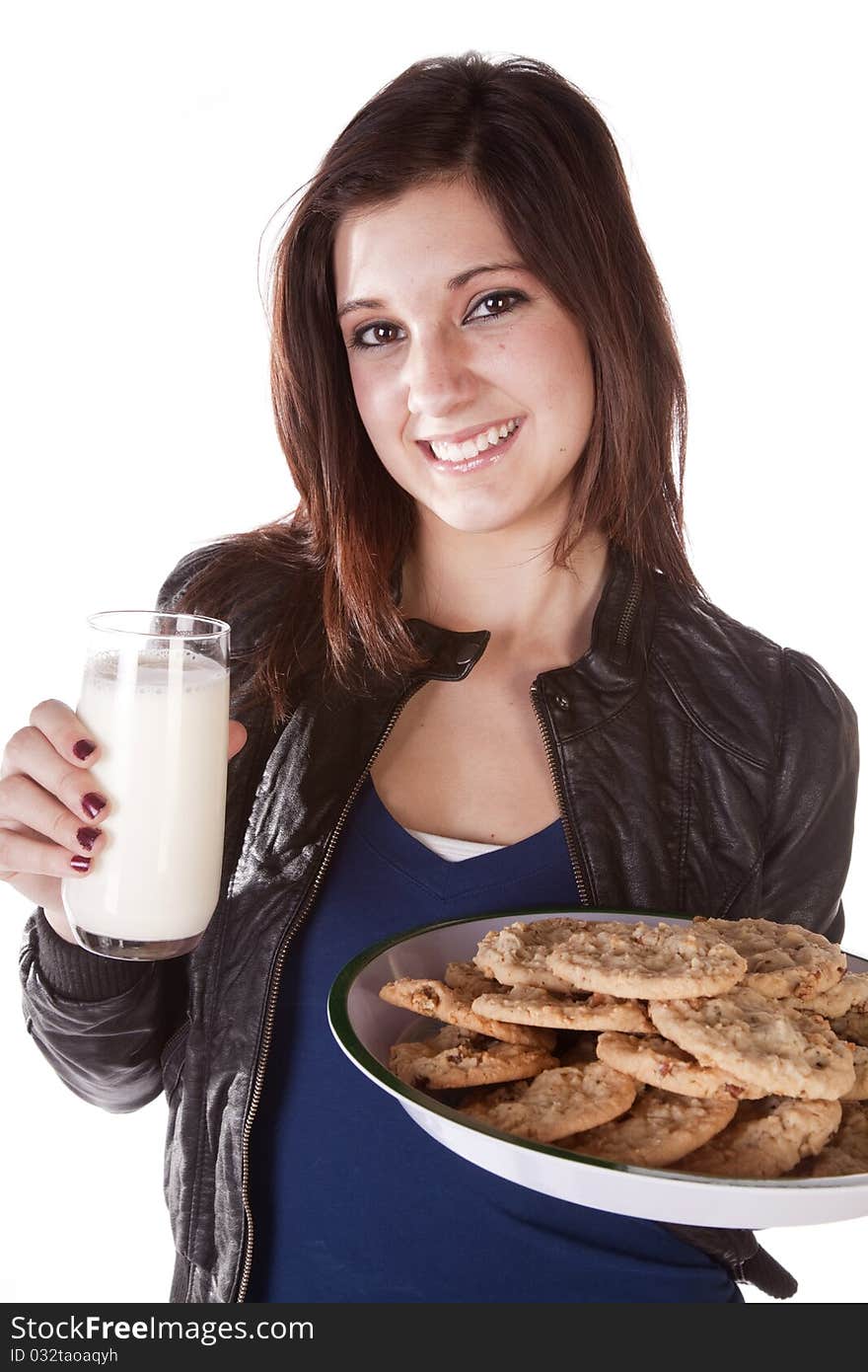 A woman holding on to a plate filled with chocolate chip cookies and in the other had a big glass of milk. She has a huge smile on her face. A woman holding on to a plate filled with chocolate chip cookies and in the other had a big glass of milk. She has a huge smile on her face.