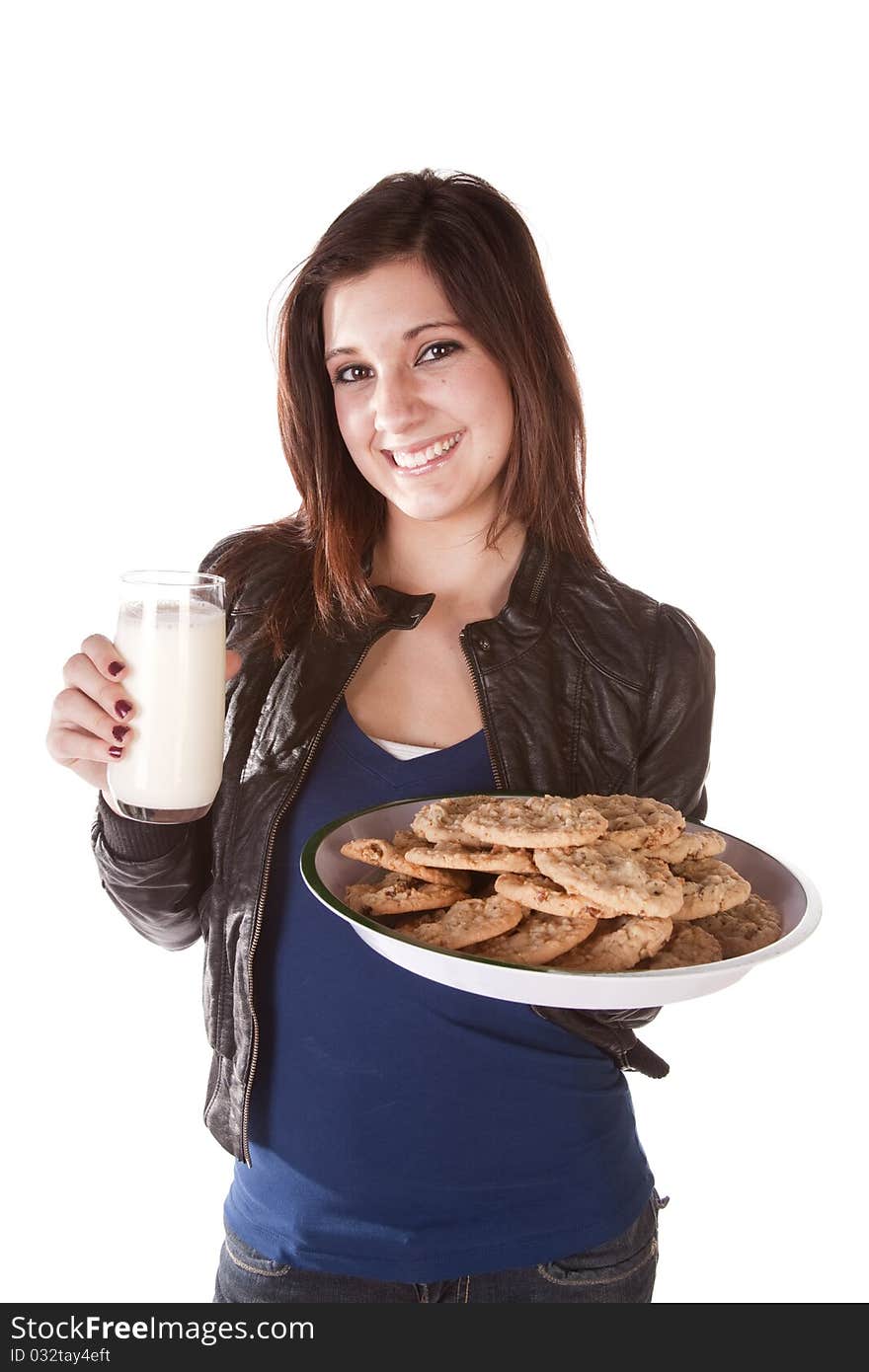 A woman holding on to a plate filled with chocolate chip cookies and in the other had a big glass of milk. She has a huge smile on her face. A woman holding on to a plate filled with chocolate chip cookies and in the other had a big glass of milk. She has a huge smile on her face.