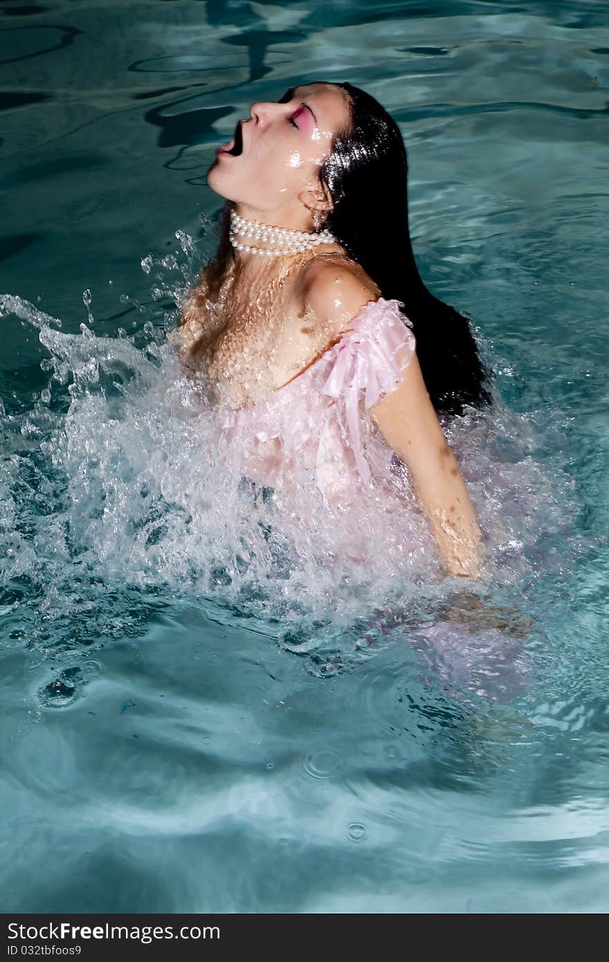 A woman in her pink dress splashing up out of the water. A woman in her pink dress splashing up out of the water.