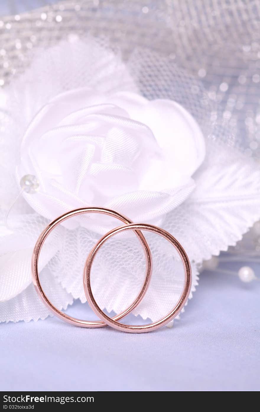 Wedding rings on blue background with satin rose