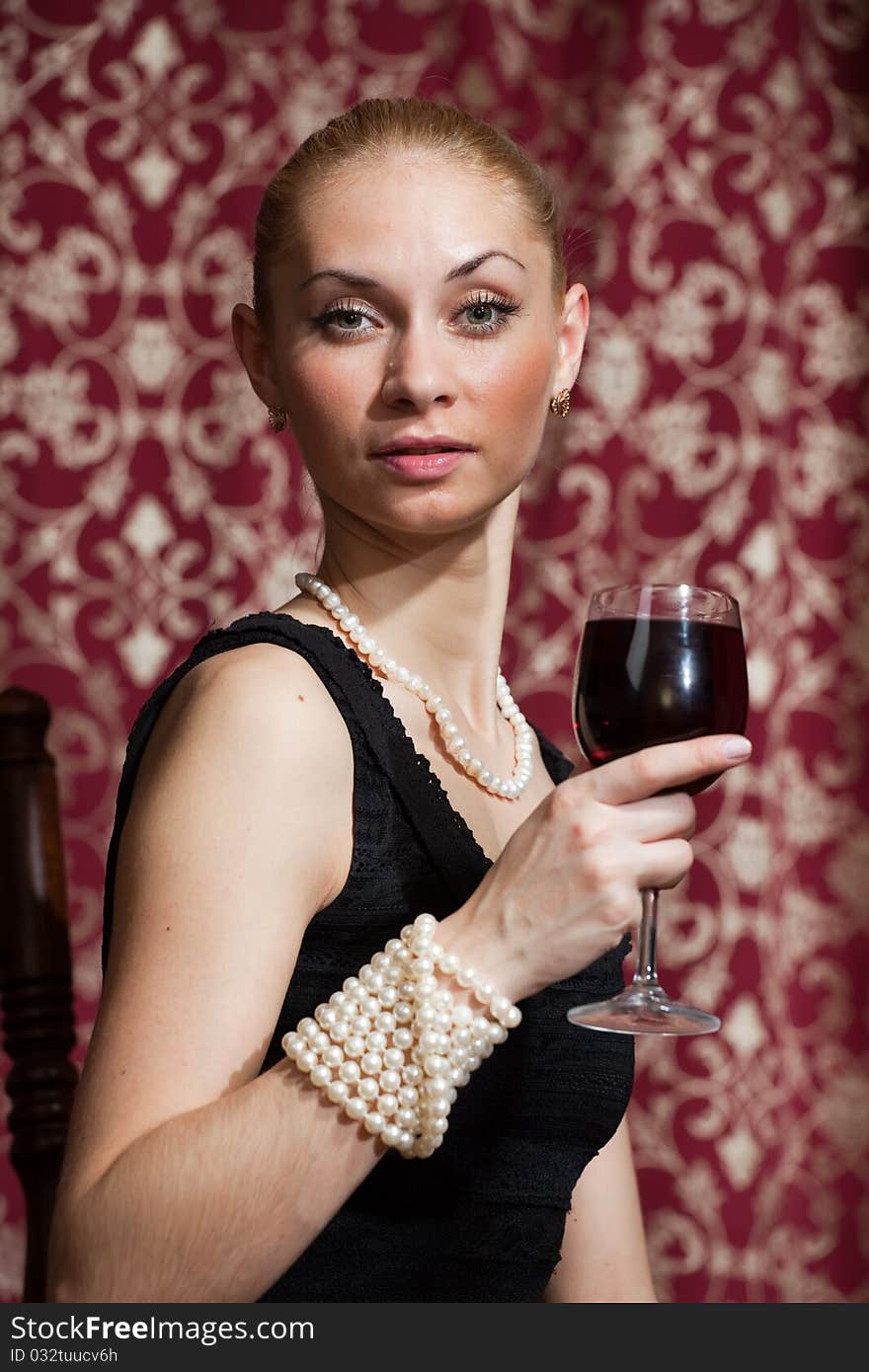 Studio portrait of a beautiful young blonde woman holding a glass of red wine. Studio portrait of a beautiful young blonde woman holding a glass of red wine