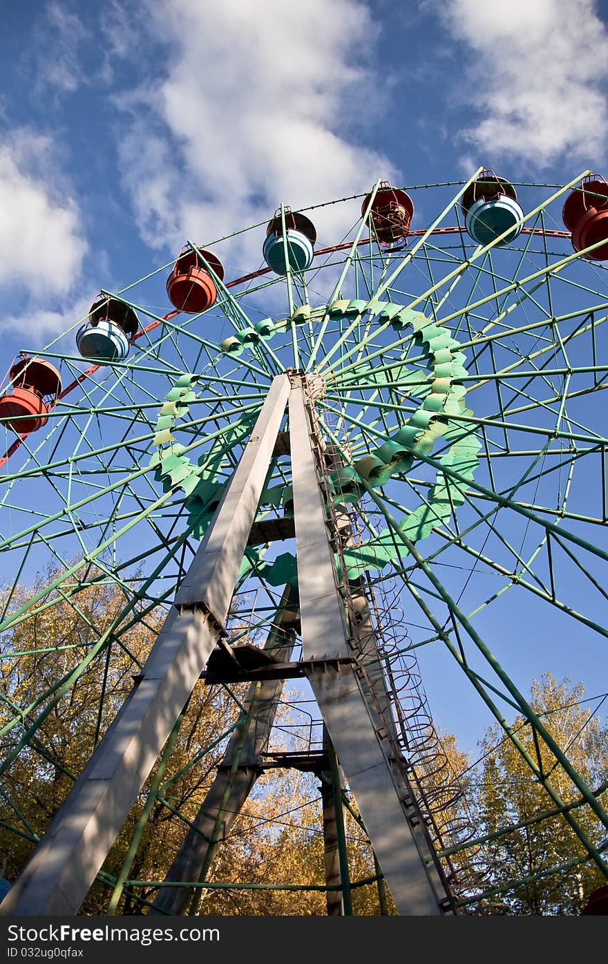 Ferris wheel in an amusement park. Autumn. Against the blue sky.