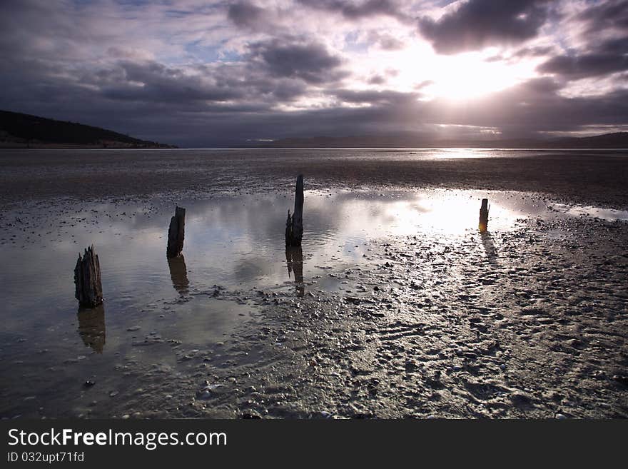 Peaceful sunset on beach in Lauderdale, with the remains of an ancient fence, Tasmania. Peaceful sunset on beach in Lauderdale, with the remains of an ancient fence, Tasmania.