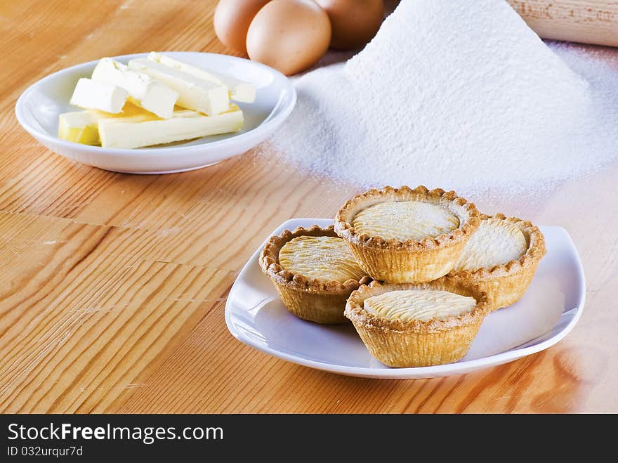 Freshly made apple pies on the table with flour eggs and butter. Freshly made apple pies on the table with flour eggs and butter