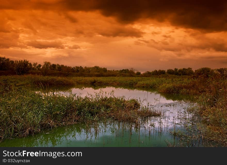 Landscape with old pond and dramatic sky