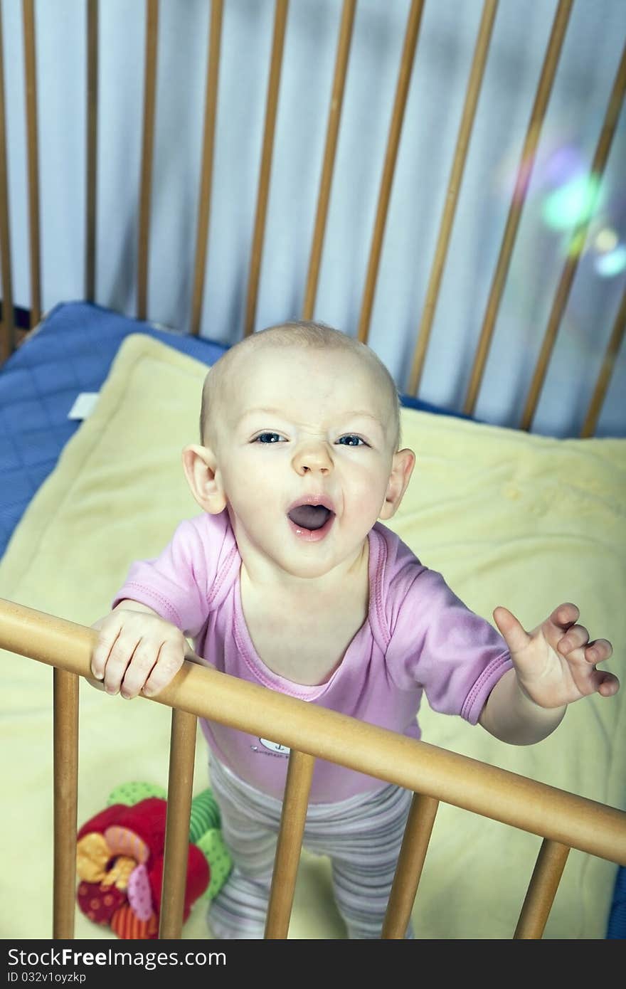 Little baby holds on to the baby bed and is happy about soap bubbles. Little baby holds on to the baby bed and is happy about soap bubbles