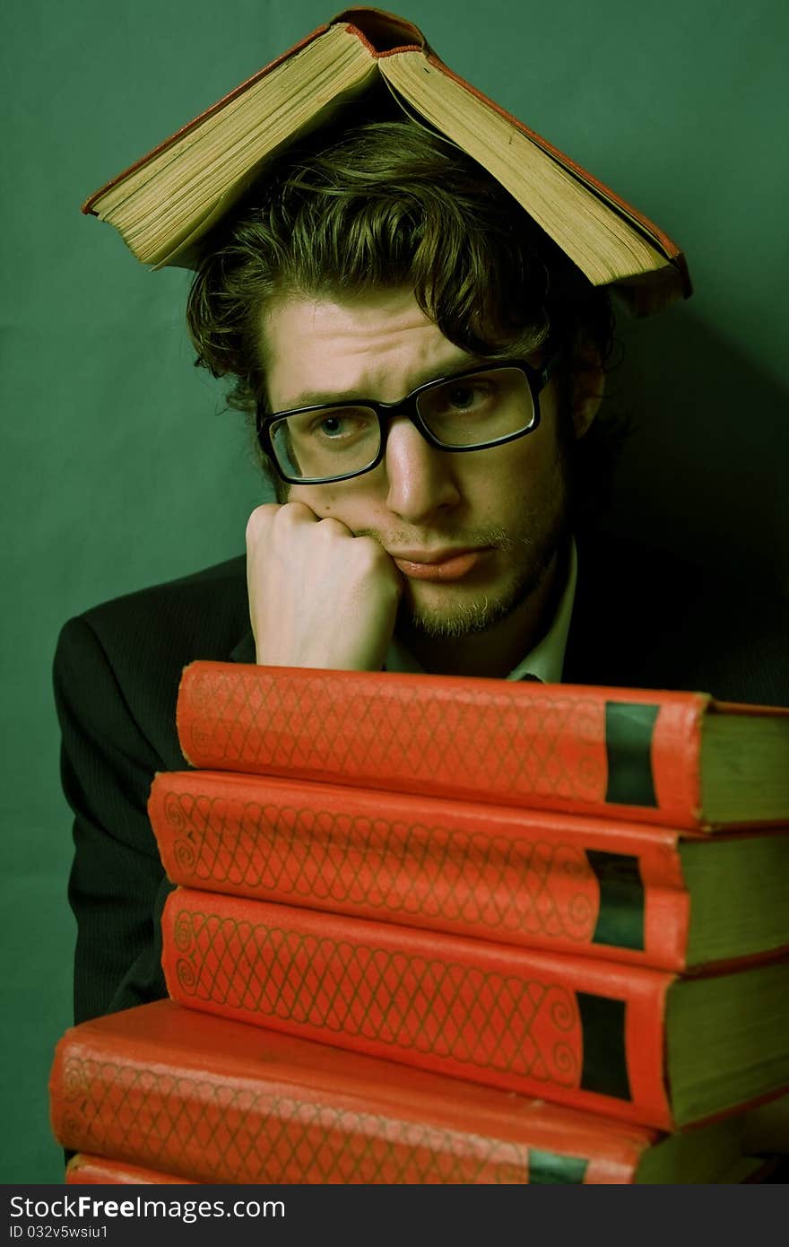 Sad young man with a stack of red books