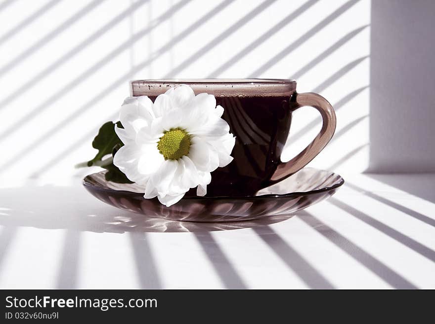 Mug of hot morning coffee and a flower