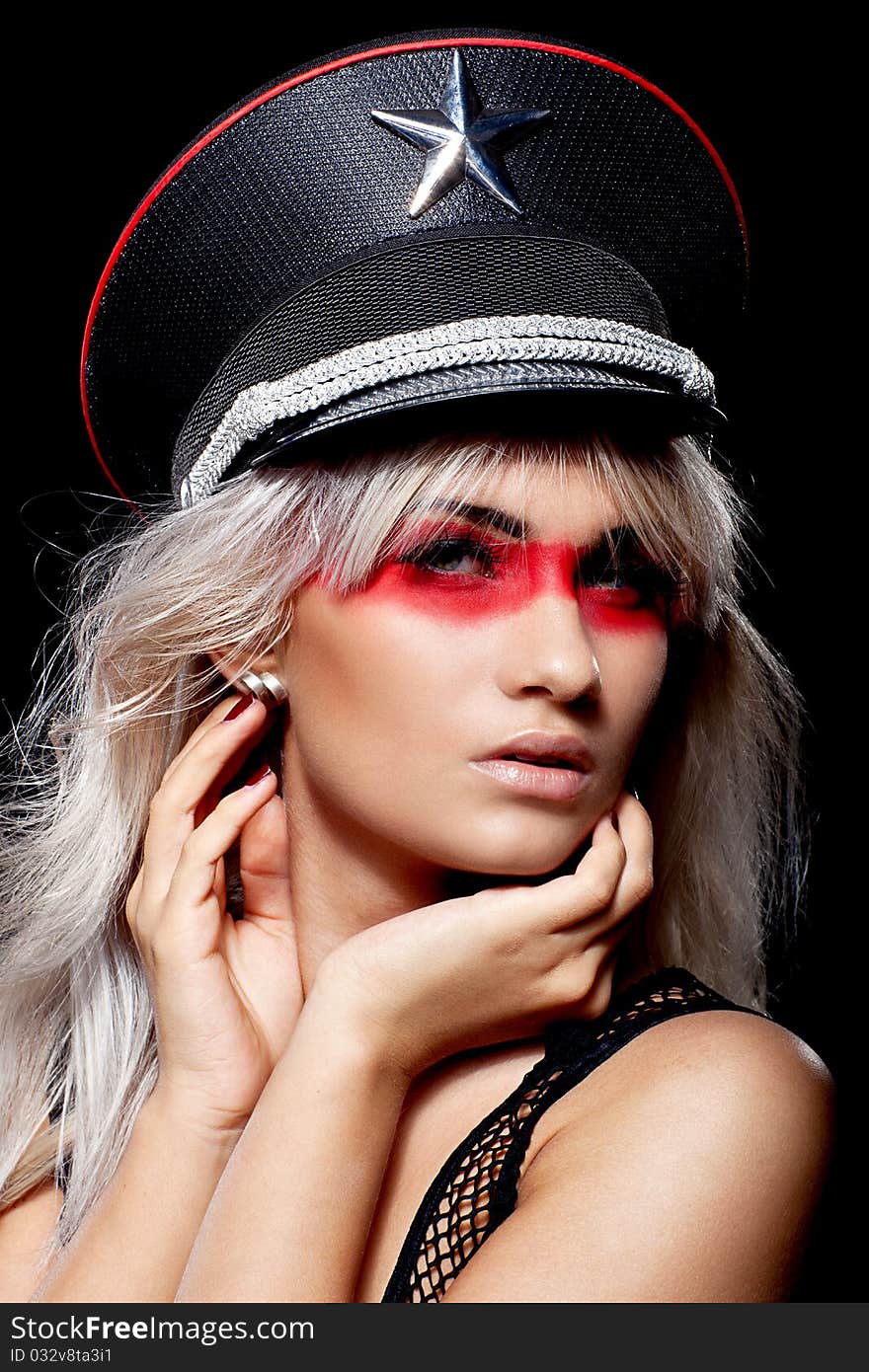 Head shot of a beautiful woman wearing peaked cap with a cockade over the black background. Head shot of a beautiful woman wearing peaked cap with a cockade over the black background