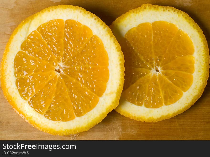 Fresh organic orange wheel pieces with peel on a wooden cutting board. Fresh organic orange wheel pieces with peel on a wooden cutting board