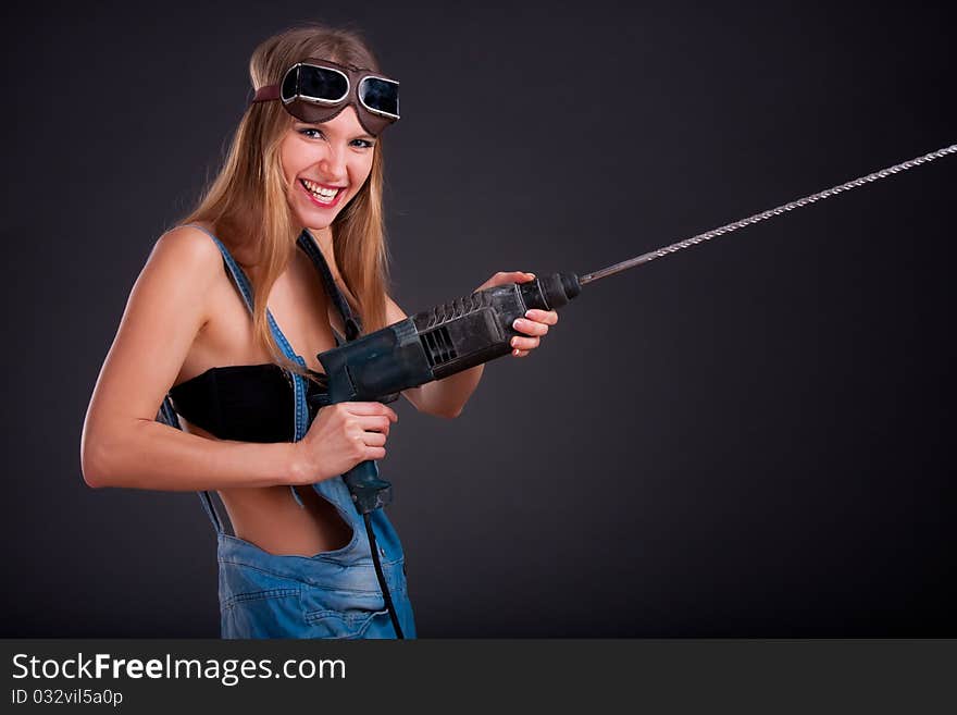 Girl with a drill in building overalls