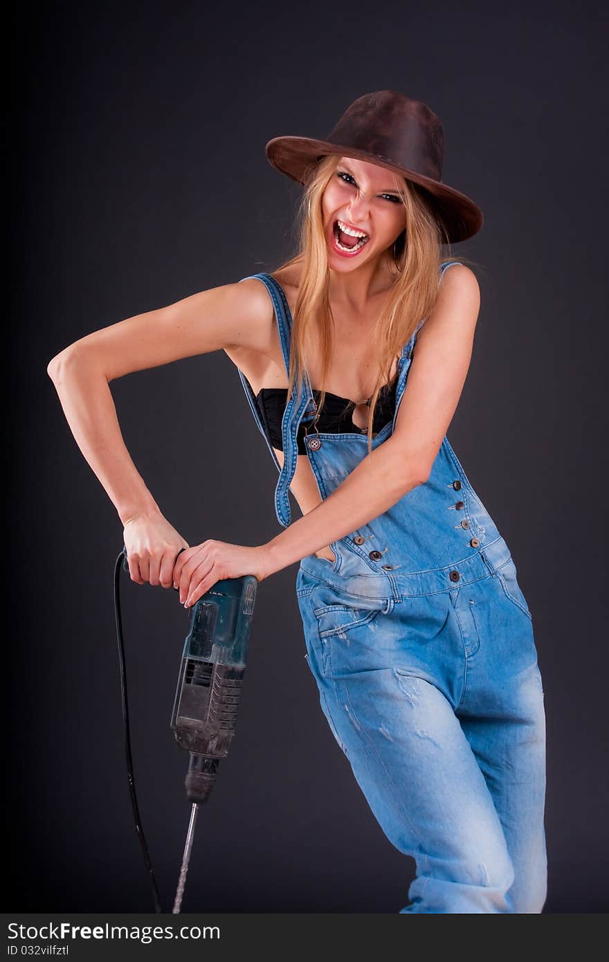 Girl with a drill in building overalls