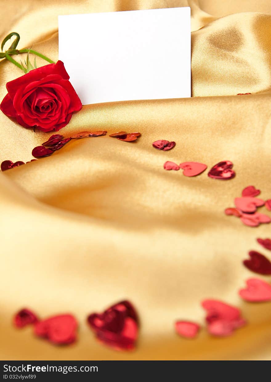 Red rose and white blank greeting card on golden satin. Red rose and white blank greeting card on golden satin