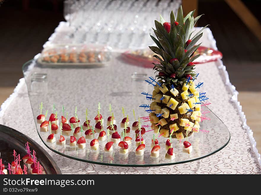 Pineapple and strawberries on skewers. Table appointments outdoors.