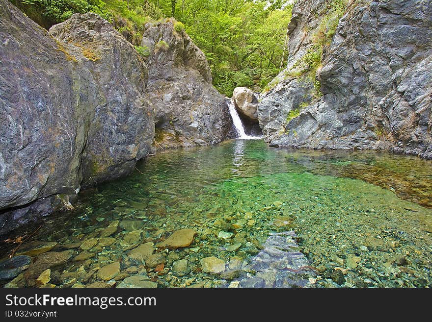 Small lake and fall between the high rocks of the river canyon, with rope for canyonists, italy. Small lake and fall between the high rocks of the river canyon, with rope for canyonists, italy