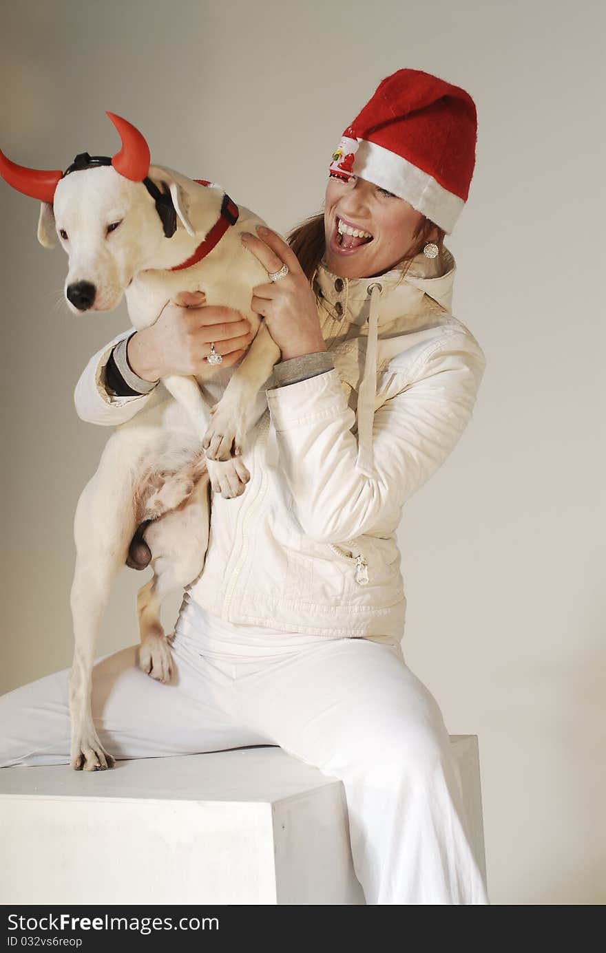 Cute girl in Xmas hat watching at white dog. Cute girl in Xmas hat watching at white dog