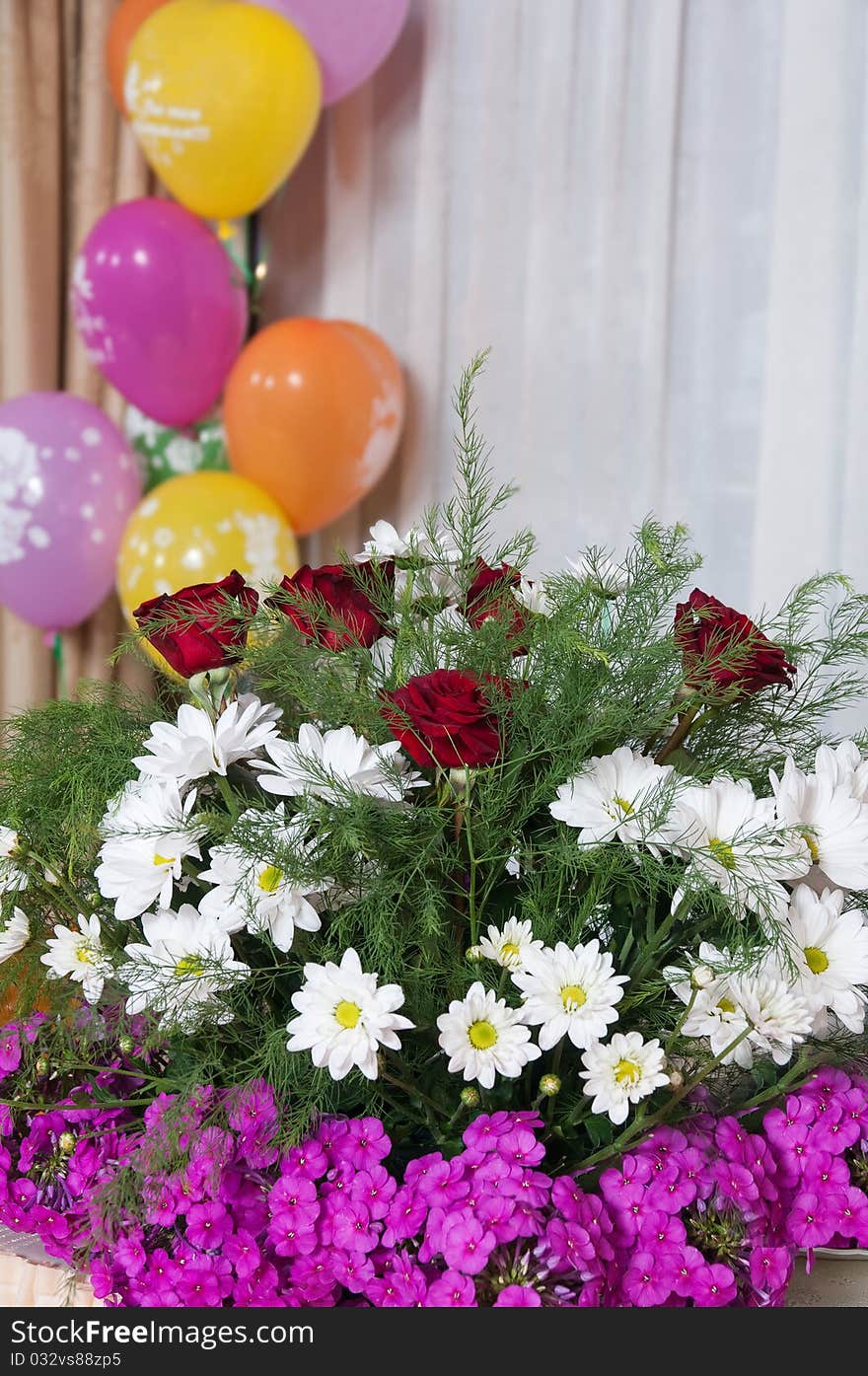 The bouquet and multi-colored balloons decorate a restaurant interior. The bouquet and multi-colored balloons decorate a restaurant interior.