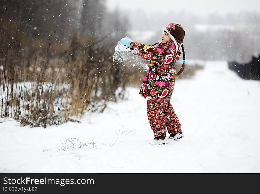 Adorable small girl in colorful winter clothes plays with snow in strong snowfall. Adorable small girl in colorful winter clothes plays with snow in strong snowfall