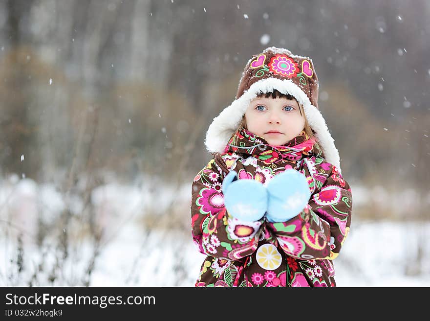 Adorable small girl in colorful winter clothes plays with snow in strong snowfall. Adorable small girl in colorful winter clothes plays with snow in strong snowfall