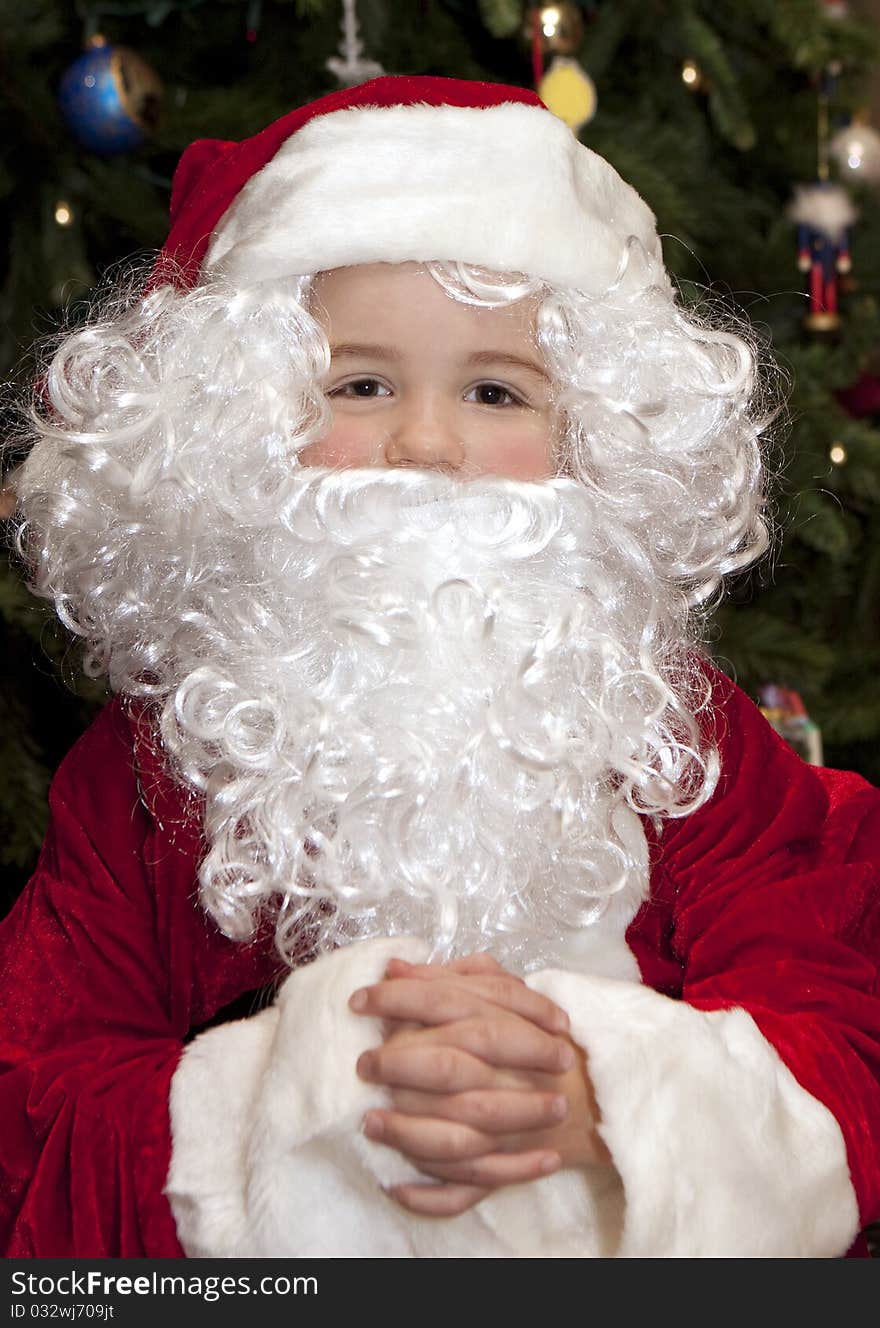 Young boy in front of Christmas tree wearing a Santa Claus suit. Young boy in front of Christmas tree wearing a Santa Claus suit.