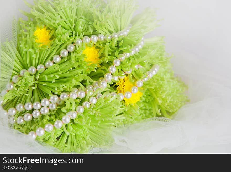 White necklace of pearls and bouquet of green chrysanthemums on a white veil. White necklace of pearls and bouquet of green chrysanthemums on a white veil