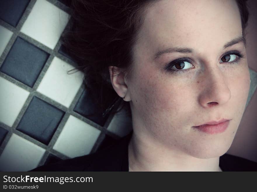 A portrait of a young redheaded woman laying on a checkerboard table. A portrait of a young redheaded woman laying on a checkerboard table.