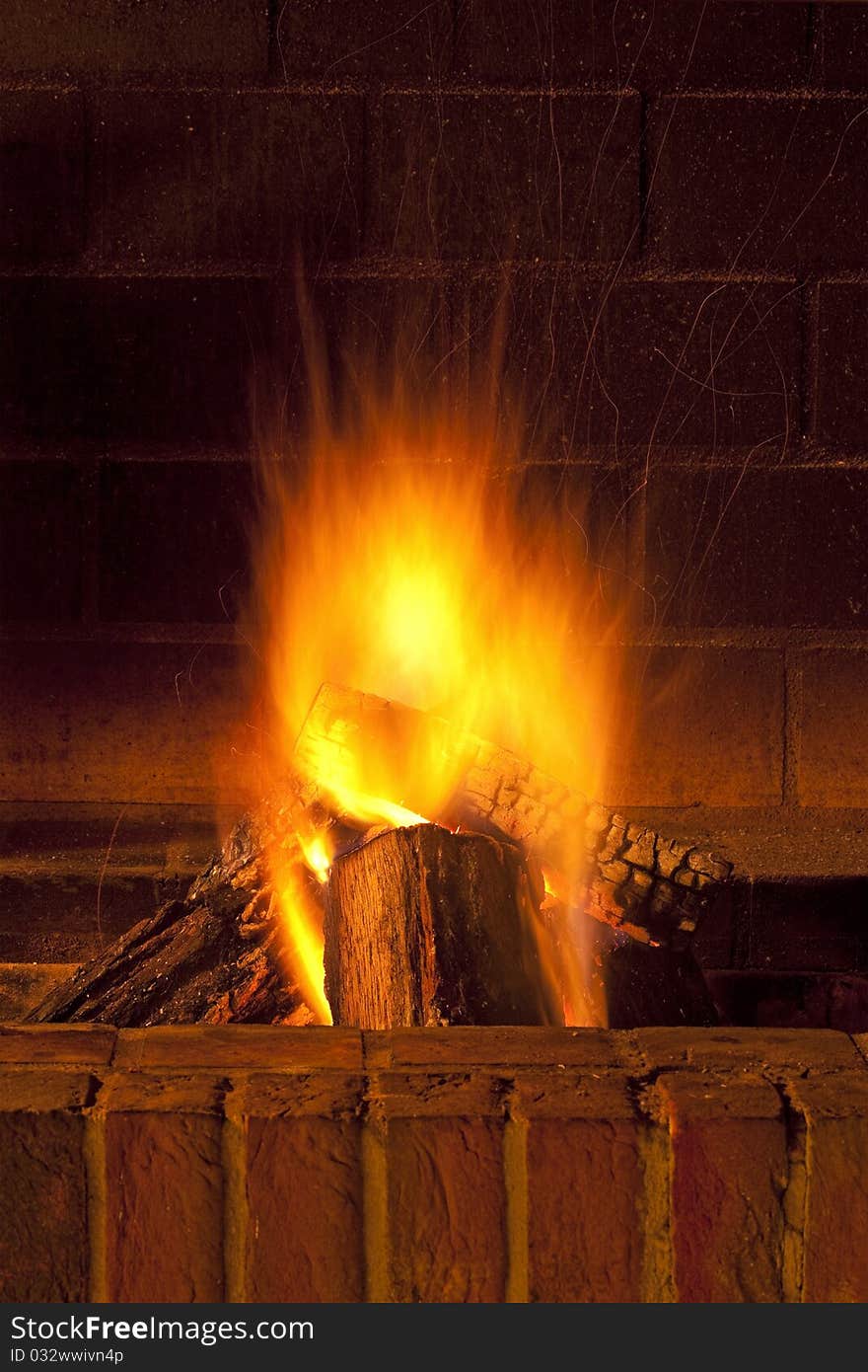 Brick fireplace with large pieces of wood burning giving warmth