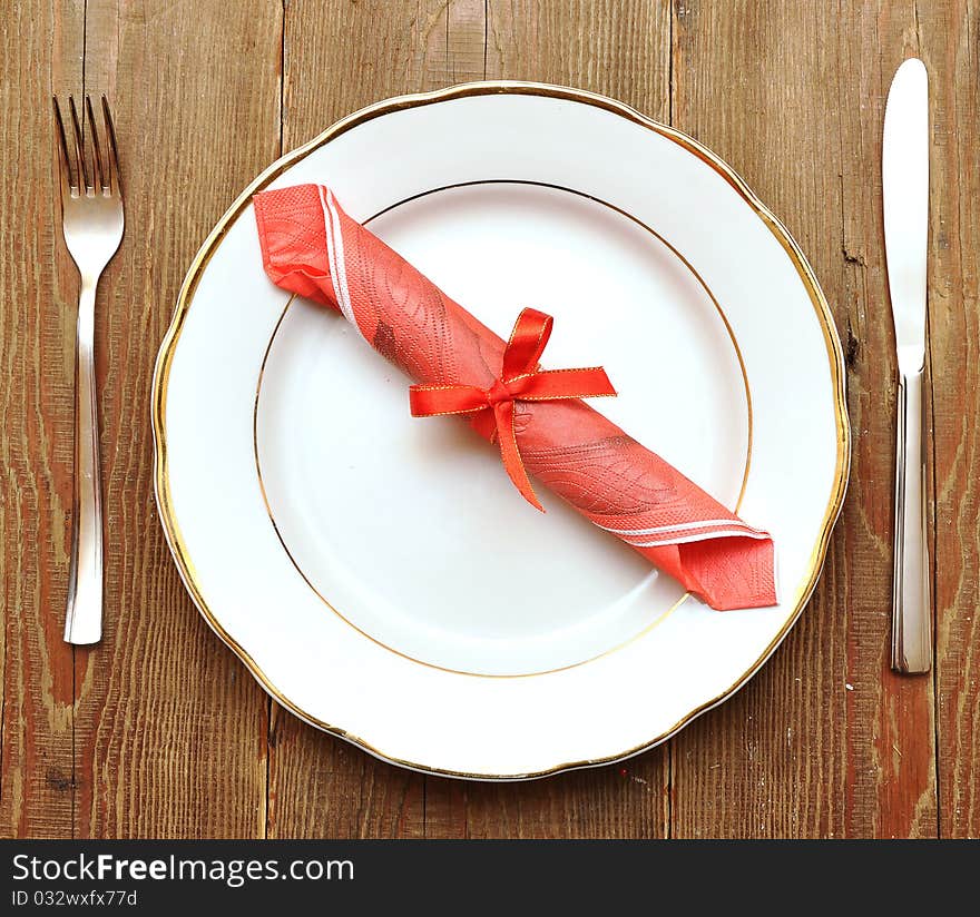 Knife, white plate and fork on old wood background