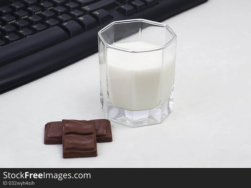 A glass of milk and two chocolate in the white background. A glass of milk and two chocolate in the white background