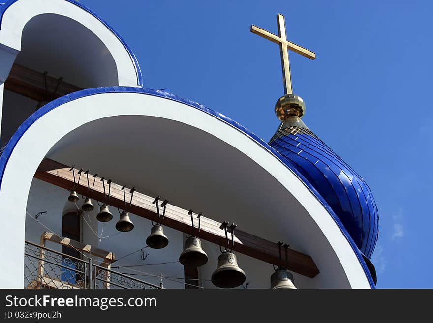 Belfry and dome with a cross against the blue sky