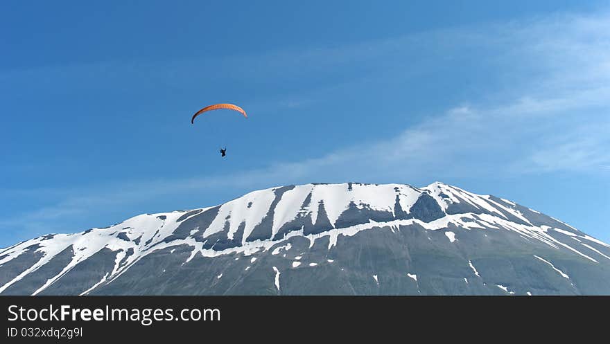 A paraglider soars over a snow-capped mountain. A paraglider soars over a snow-capped mountain