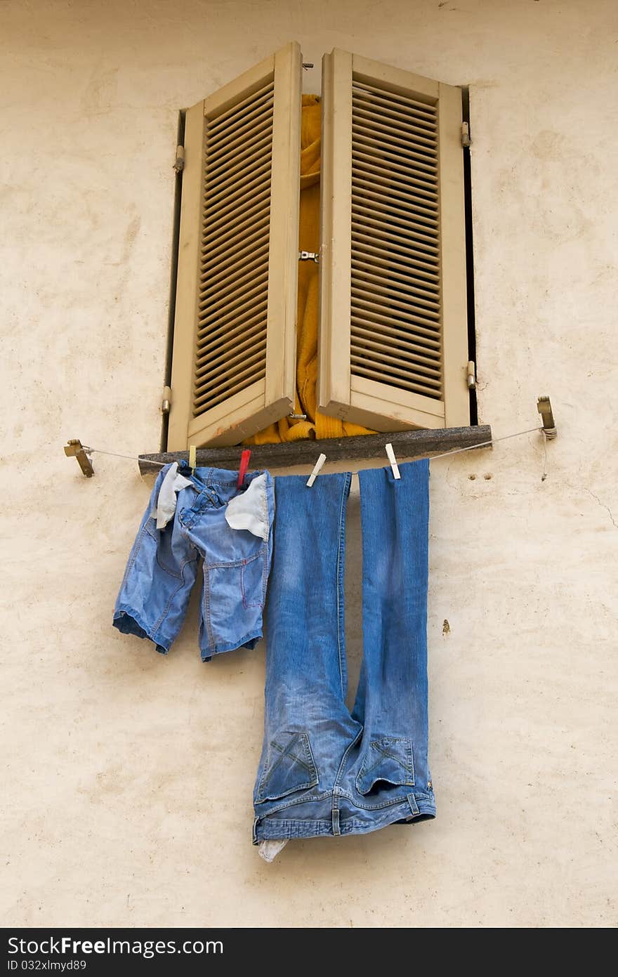 Jeans hanging out of shuttered Italian window to dry. Jeans hanging out of shuttered Italian window to dry