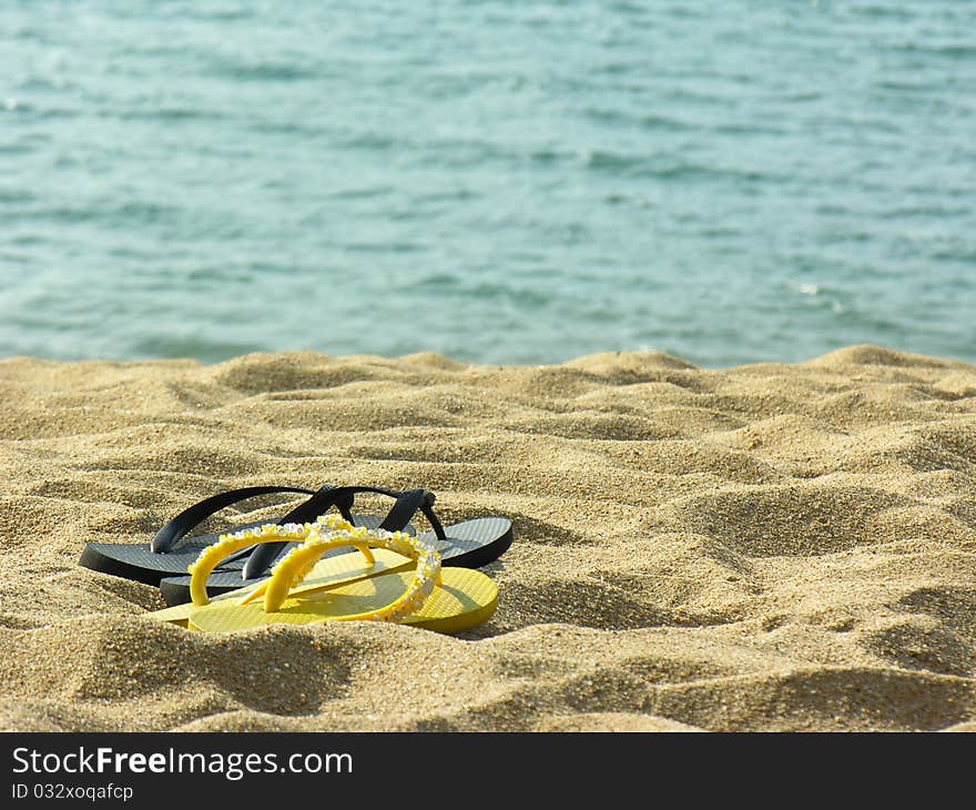 Summer flip-flop on the sand with the ocean at the background. Summer flip-flop on the sand with the ocean at the background.