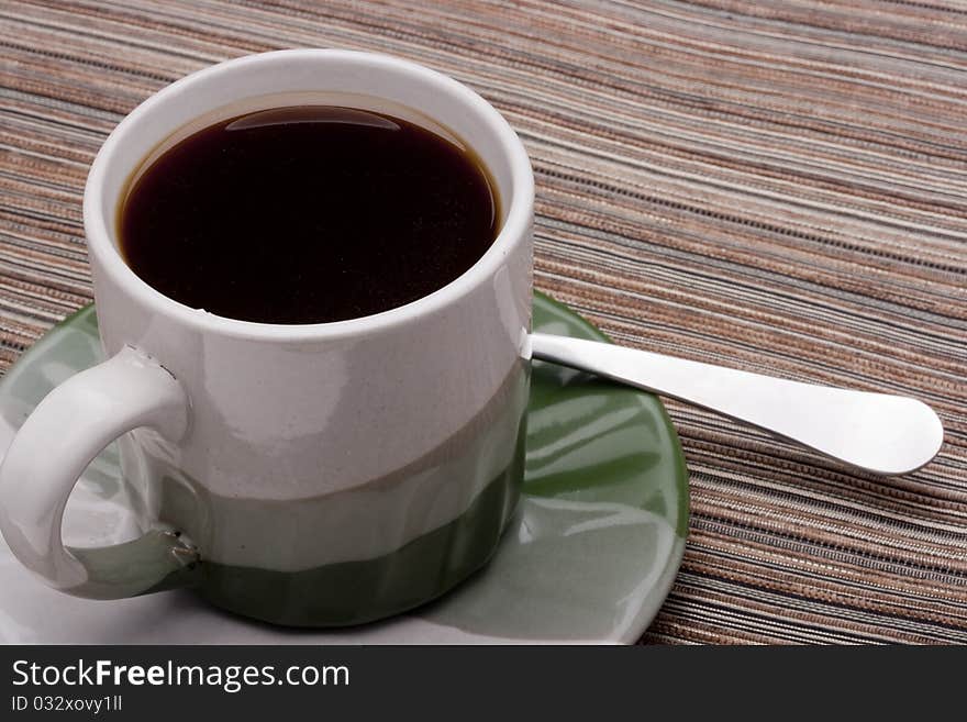 Ceramic mug and saucer with greyish green for hot drinks.