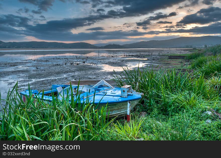 Old boat at lakeside at sunrise