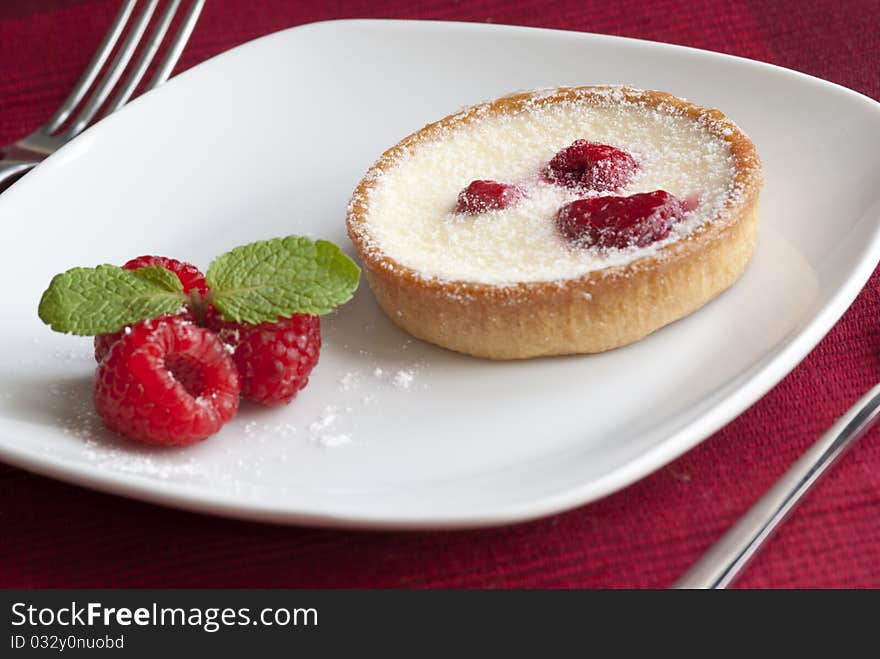 Raspberry and custard tart decorated with fresh mint. Raspberry and custard tart decorated with fresh mint