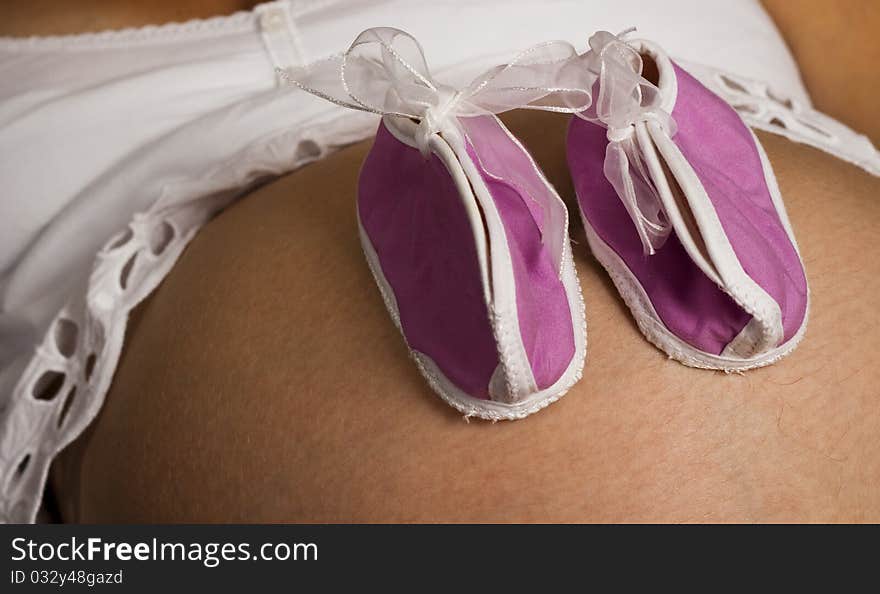 Pink baby shoes on a black and white pregnant belly