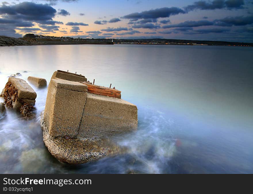 The remnants of an old railway lay abandoned in the sea, the structures are being eroded and reclaimed by nature. The remnants of an old railway lay abandoned in the sea, the structures are being eroded and reclaimed by nature.