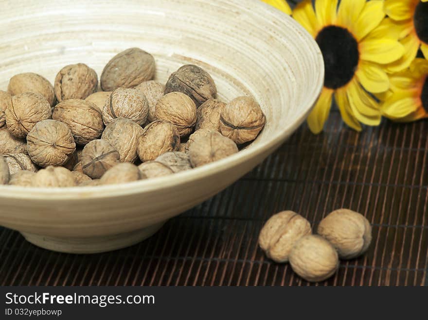 Wooden bowl with walnuts on mat