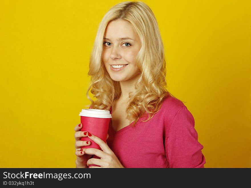 Beautiful young woman on a yellow background holding a paper cup of coffee. Beautiful young woman on a yellow background holding a paper cup of coffee