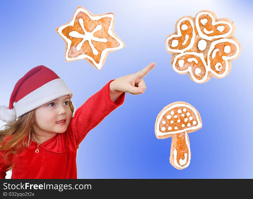 Little girl in Christmas hat pointing to cookie, isolated on white